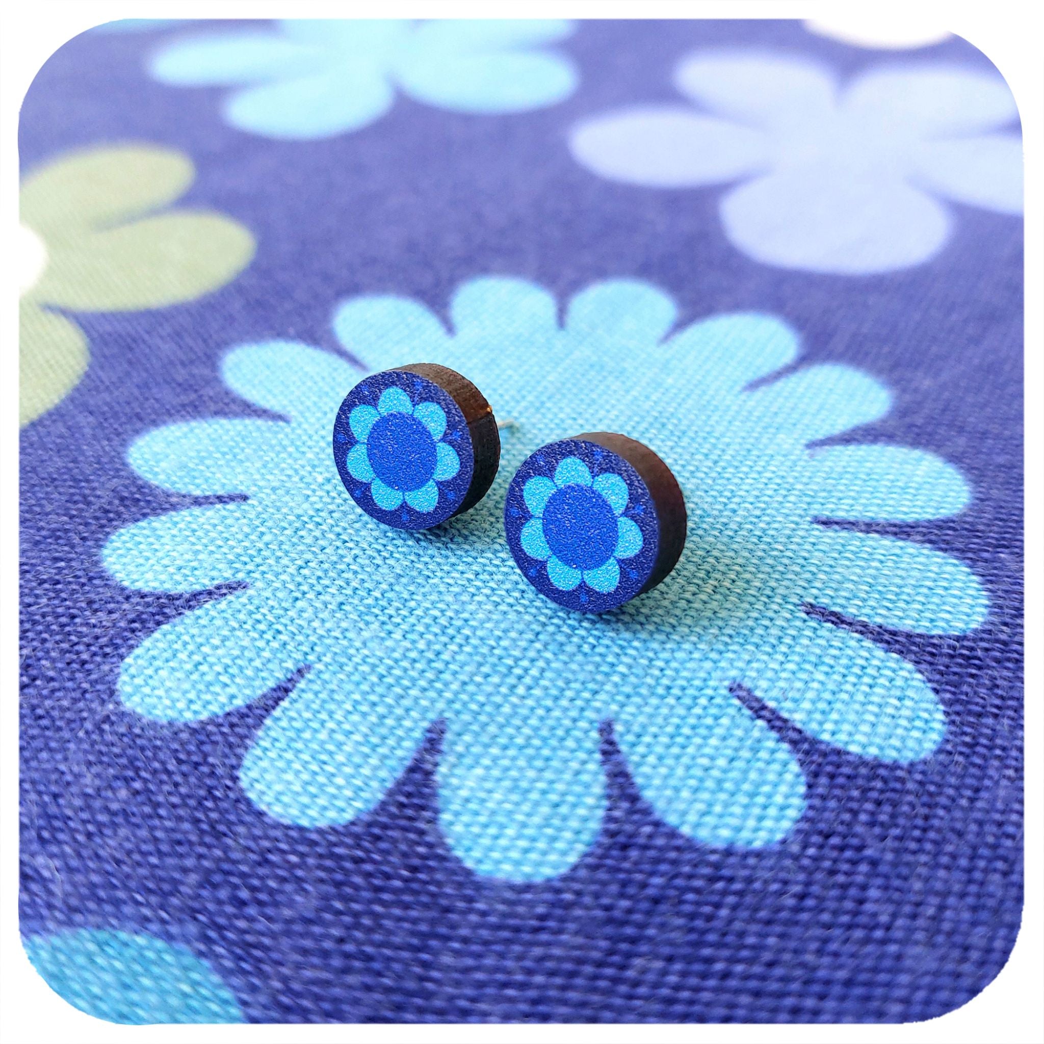 Blue flower-shaped earrings on a blue floral background