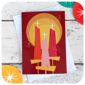 Mid Century Modern style Christmas Card featuring candles and starburst motifs, with a white envelope, on a white table with 50s style xmas decorations | The Inkabilly Emporium