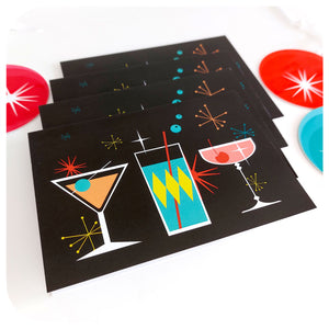 Four Cosmic Cocktails Christmas Cards, on a white table with retro Christmas decorations | The Inkabilly Emporium