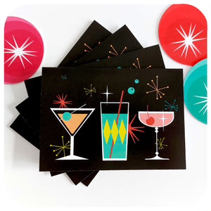 Four Cosmic Cocktails Christmas Cards, on a white table with retro Christmas decorations | The Inkabilly Emporium