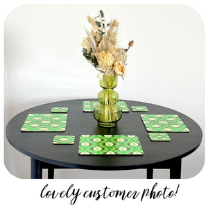 70s Style Green Placemats and coasters on a black table with green glass vase holding dried flowers.
