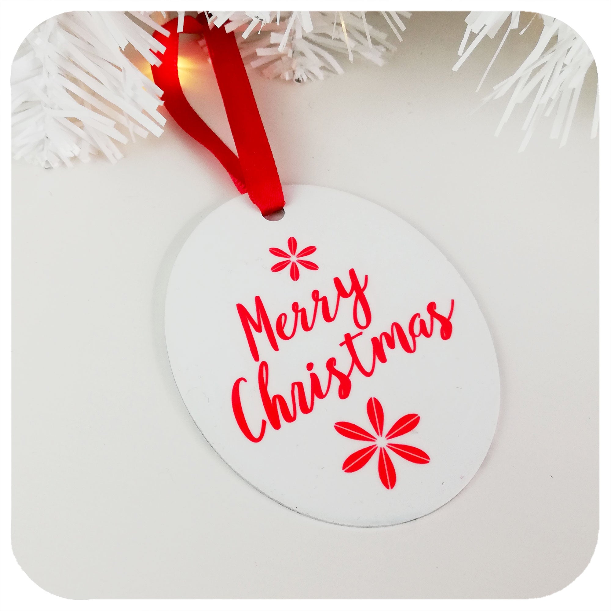 Christmas Tree Decoration saying 'Merry Christmas' in red & white, hanging by red ribbon on a white table | The Inkabilly Emporium