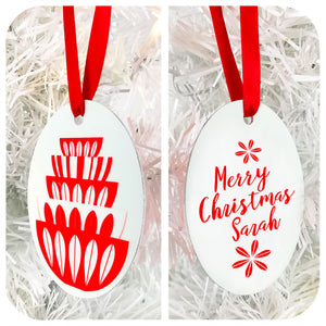 Double image of a Personalised Catherineholm inspired Christmas Tree Decoration saying 'Merry Christmas Sarah' in red & white, hanging by red ribbon on a white Christmas tree | The Inkabilly Emporium